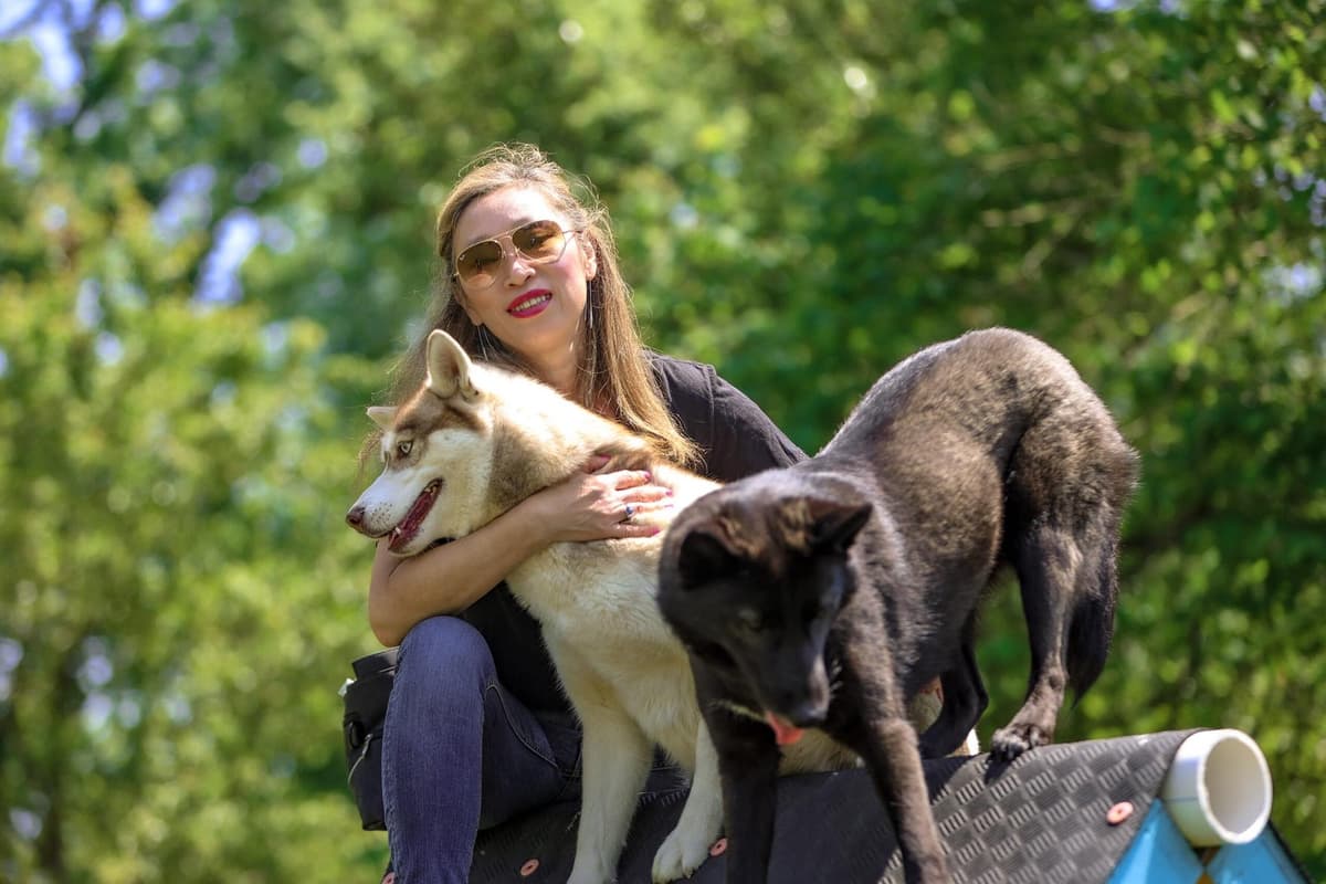 Nicole Buck outdoors with a husky and a working-line dog